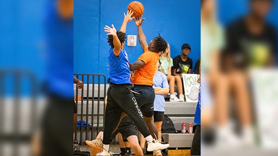 Two basketball players jump up simultaneously to reach the basketball on a court. 他们都穿着运动服.